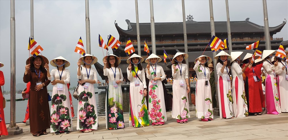 Đoàn thanh niên phật tử trong trang phục áo dài, nón lá vẫy cờ chào mừng lãnh đạo, đại biểu dự đại lễ.