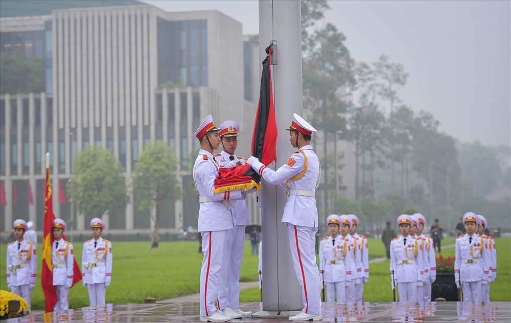 Ba chiến sĩ thực hiện nghi thức trang trọng tại chân cột cờ. Nghi lễ treo băng tang được tiến hành song song với nghi thức chào cờ thường ngày.
