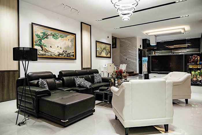 Không gian nổi bật với bộ sofa trắng đen sang trọng và nhiều tranh ảnh trang trí.