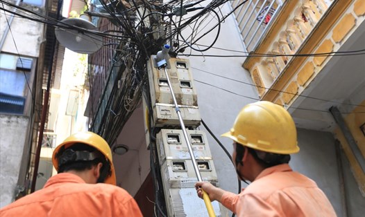 Công nhân đo chỉ số côngtơ điện của người dân trên phố Thái Hà. Ảnh: HẢI NGUYỄN