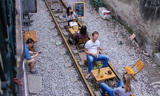 Ảnh: Khách nước ngoài thích thú ngồi uống cà phê trên đường ray tàu hỏa ở Hà Nội.
