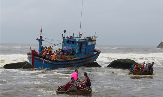  Lực lượng chức năng cùng ngư dân đang cứu nạn tàu cá bị sóng xô vào đá ở cửa biển Mỹ Á. Ảnh: PV