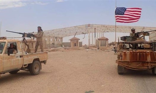 Một phiến quân trên chiếc xe được trang bị súng máy hạng nặng (bên trái) gần một binh sĩ Mỹ trên xe bọc thép tại trạm kiểm soát biên giới Syria-Iraq ở Tanf. Bức ảnh chụp vào ngày 23.5.2017. Ảnh: AP