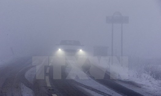 Ô tô di chuyển trên đường trong tuyết và sương mù dày đặc tại Derbyshire, miền bắc nước Anh. Ảnh: AFP/TTXVN
