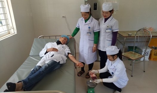 Kỹ thuật viên Đinh Văn Sơn (Khoa Xét nghiệm, Bệnh viện Bắc Yên, người nằm) hiến máu để cứu sản phụ Lầu Thị Chà. Ảnh: Lường Thị Chuyển