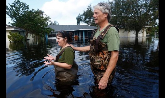 Cặp đôi đi trên đường phố ngập lụt ở bang Florida. Ảnh: CNN