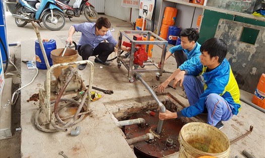 Nhân viên cây xăng An Bình trên đường Trần Phú (Hà Đông, Hà Nội) xúc rửa hầm chứa để đón xăng E5 RON 92 đầu tiên tại cửa hàng. Ảnh: ĐỨC THÀNH