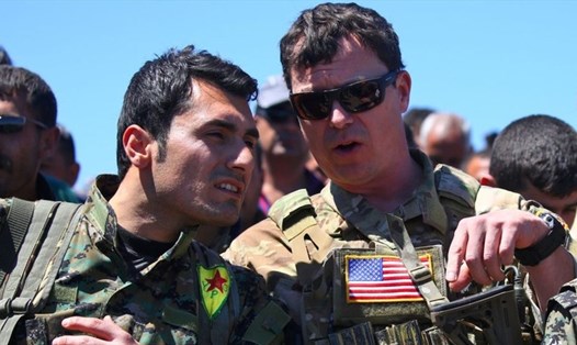 Binh sĩ Mỹ (phải) nói chuyện với chiến binh người Kurd ở Derik, Syria. Ảnh: Getty Images