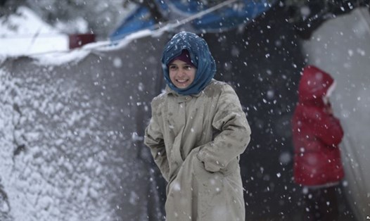 Một bé gái Syria đang giữ ấm khi tuyết rơi tại Idlib. Ảnh: Reuters