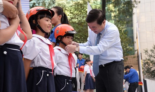 Chủ tịch UBND TPHCM Nguyễn Thành Phong tặng nón bảo hiểm cho các em học sinh.  Ảnh: M.Q