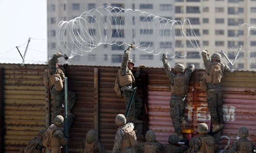 Lính Mỹ dựng dây thép gai lên bức tường biên giới ở San Diego. Ảnh: Reuters