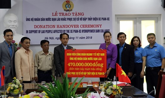 Chủ tịch CĐ Y tế VN Phạm Thanh Bình (phải) trao 20 nghìn USD cho đồng chí Ingpeng - Trưởng ban Đối ngoại, Trung ương Liên hiệp CĐ Lào để ủng hộ nhân dân Lào bị thiệt hại trong sự cố vỡ đập thuỷ điện Xe-Pian Xe-Namnoy.