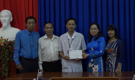 Chủ tich Công đoàn Y tế tỉnh Cà Mau Lý Thị Loan (phải) trao hỗ trợ cho điều dưỡng Phan Văn Ân.