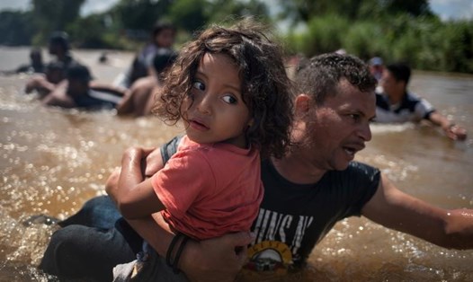 Luis Acosta cùng cô bé Angel Jesus 5 tuổi (Honduras) di cư từ Trung Mỹ trên đường đến Hoa Kỳ băng qua sông Suchiate vào Mexic, ngày 29 tháng 10. Ảnh: REUTERS 