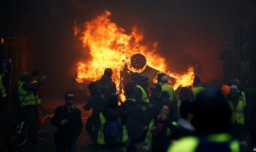 Những người biểu tình mặc áo gile vàng tụ tập gần một chiếc xe bị đốt cháy ở quảng trường Place de l'Étoile ở Paris, Pháp, ngày 1.12.2018. Ảnh: Reuters