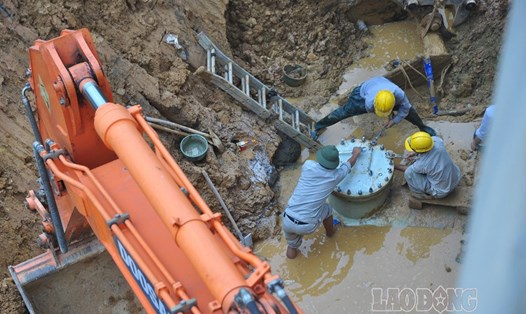 Các công nhân Công ty nước sạch Vinaconex khắc phục sự cố vỡ đường ống nước lần thứ 7 đoạn qua cầu Đồng Trúc (Thạch Thất, Hà Nội). ẢNH: Thành An.