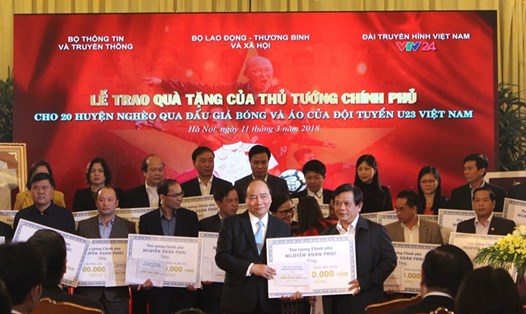 Thủ tướng Nguyễn Xuân Phúc trao kinh phí đấu giá áo và trái bóng của U23 Việt Nam cho 20 huyện nghèo trên cả nước. Ảnh PV