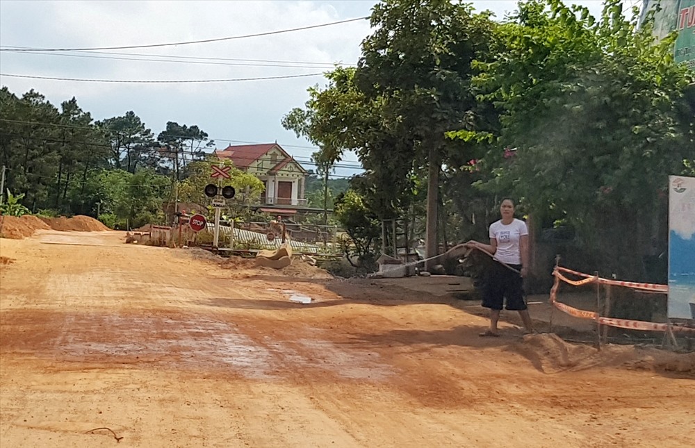 Dân sống hai bên đường phải tự tưới nước để giảm bụi ô nhiễm. Ảnh: Lê Phi Long