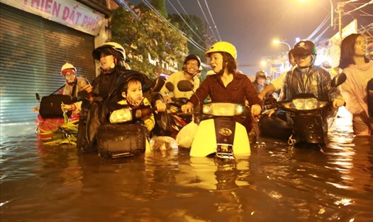 Người dân bì bõm dắt xe máy trên đường Phan Huy Ích (quận Gò Vấp) sau cơn mưa tối 19.5.  Ảnh: Ngọc Tiến