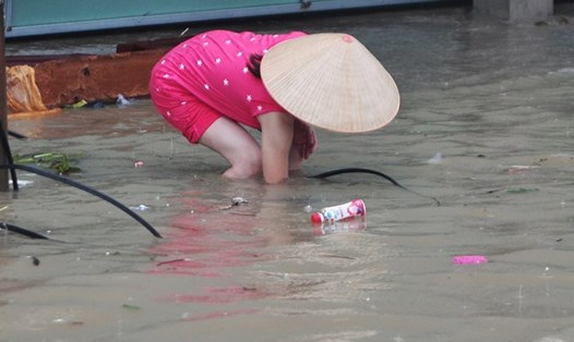 Một người dân mò mẫm dọn rác để khơi miệng cống thoát nước trên đường Bùi Văn Hòa (TP Biên Hòa). 