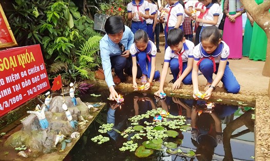 Thầy Hiệu trưởng và các em học sinh trường Tiểu học Hướng Phùng thả hoa đăng tưởng niệm 64 anh hùng liệt sĩ hi sinh trong trận Gạc Ma. Ảnh: PV