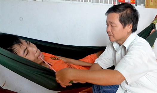 Thầy Hồng chăm sóc con trai Văn Thành Thống. (Ảnh: Lục Tùng)