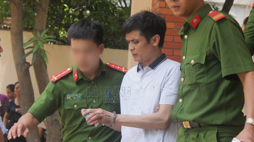 Cảnh sát dẫn giải ông Nguyễn Đình Lê (giáo viên Trường Tiểu học An Thượng A) ra xe sau khi kết thúc phiên tòa xét xử. 