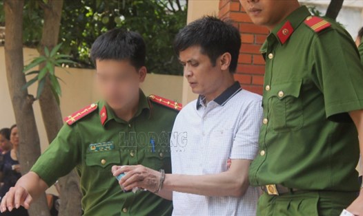 Cảnh sát dẫn giải ông Nguyễn Đình Lê (giáo viên Trường Tiểu học An Thượng A) ra xe sau khi kết thúc phiên tòa xét xử. 