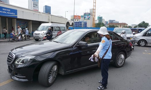 Nhân viên thu phí hướng dẫn cho xe ôtô vào đậu tại điểm đỗ xe ôtô có thu phí trên đường Phan Bội Châu (Q.1, TPHCM). Ảnh: MINH QUÂN