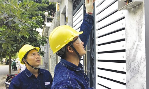 Anh Nguyễn Văn Trọn (bên trái) cùng đồng nghiệp kiểm tra hộp bảo vệ điện kế có gắn kính cường lực.