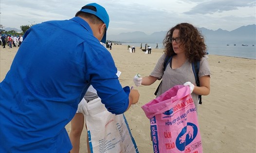 Du khách nhặt rác cùng người dân Đà Nẵng làm sạch biển.