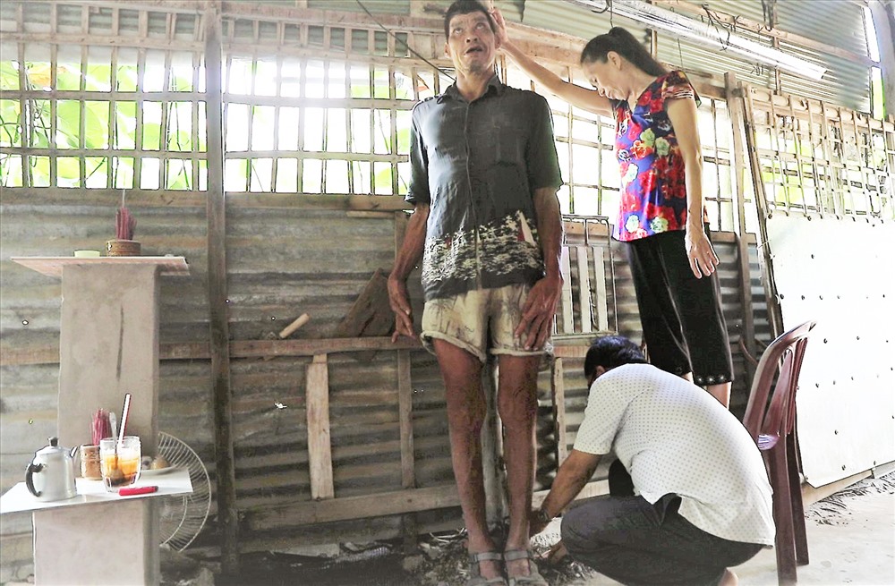 Hai vợ chồng người em út đo chiều cao của ông Y. Trước đây có người đo ông cao 2,15m nhưng do tuổi cao sức yếu nên giờ chỉ đo được 2,01m. Ảnh: Trường Sơn