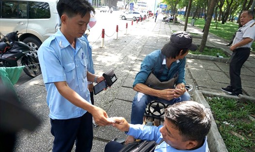 Nhân viên thu phí chuyển phiếu đỗ xe cho tài xế trên một con phố ở Q.1 (TPHCM). Ảnh: MINH QUÂN