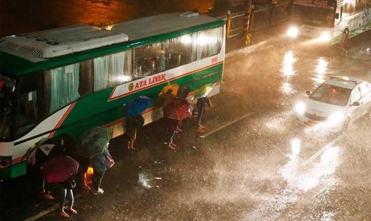 Người đi bộ và các phương tiện giao thông đi chuyển trong mưa lớn và gió mạnh ở Philippines sáng 15.9. Ảnh: AP. 