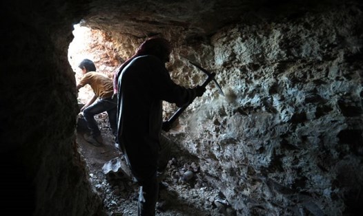 Một người đàn ông đang dùng cuốc mở rộng một hang ở Kafr Ain, phía nam tỉnh Idlib, Syria. Ảnh: AFP. 