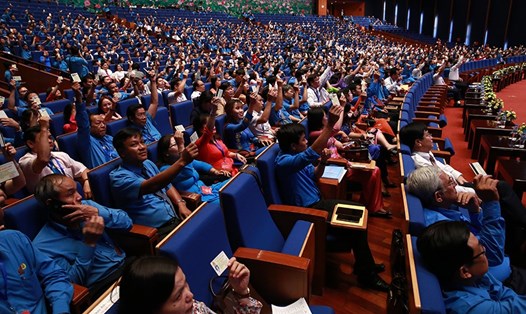 Các đại biểu biểu quyết bằng cách giơ thẻ đoàn viên tại Đại hội XII Công đoàn Việt Nam. Ảnh: HẢI NGUYỄN