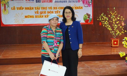 Ngoài vé xe về quê ăn Tết, chị Lô Thị Hậu (trái) còn được bà Nguyễn Thị Phượng - Phó Tổng Giám đốc Agribank tặng một món quà đặc biệt của ngân hàng. Ảnh: P.V