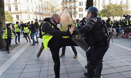 Một người biểu tình mặc gile vàng và đeo mặt nạ phòng độc cố gắng đá một sĩ quan cảnh sát chống bạo động tại trung tâm thành phố Nantes, miền tây nước Pháp.