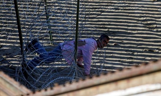 Người đàn ông này bò qua hàng rào dây thép gai để vượt biên, hy vọng trở thành công dân Mỹ để thoát tình trạng bạo lực và đói nghèo ở quê hương. Ảnh: Reuters.
