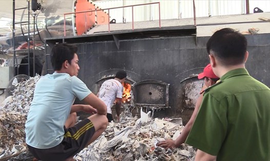 Công nhân đổ rác thải công nghiệp vào lò đốt của công ty sản xuất giấy.
