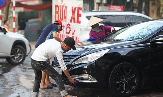 Nhiều điểm rửa xe tại Hà Nội lấn chiếm vỉa hè, lòng đường, xả thải thẳng ra môi trường. Ảnh: PV