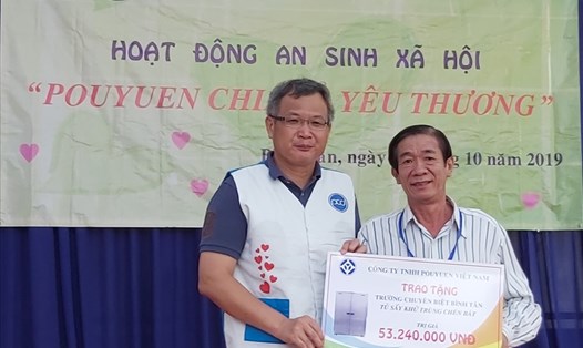 Ông Thái Văn Tông (bên trái) Giám đốc điều hành Tập đoàn PouYuen khu vực Việt Nam, tặng biển tượng trưng tủ sấy khử trùng chén bát cho Trường Chuyên biệt Quận Bình Tân. Ảnh Nam Dương