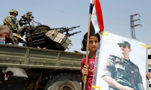 Một bé gái cầm ảnh của Tổng thống Syria Bashar al-Assad. Ảnh: Reuters