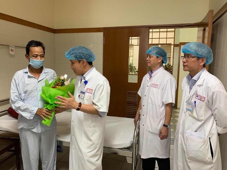 GS.TS Phạm Như Hiệp - Giám đốc Bệnh viện Trung ương Huế (phải), tặng hoa và căn dặn bệnh nhân Tý trước khi ra viện.