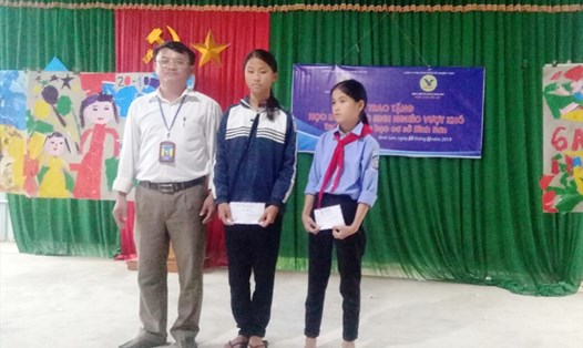 Hiệu trưởng trường THCS Bình Sơn (Anh Sơn - Nghệ An) trao học bổng cho 2 học sinh. Ảnh: PV