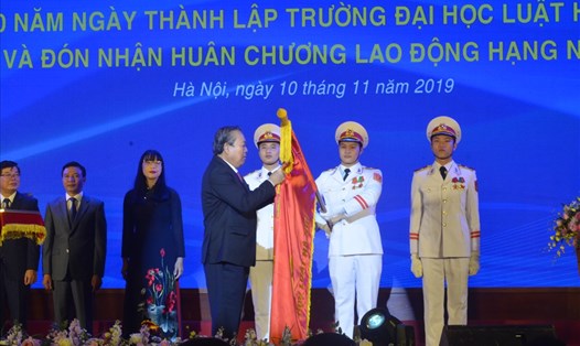 Phó Thủ tướng Thường trực Chính phủ Trương Hòa Bình gắn Huân chương Lao động hạng Nhất lên lá cờ truyền thống của trường tại lễ kỷ niệm.