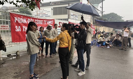 Công nhân Cty VMEP đội mưa phản ánh vụ việc với phóng viên Báo Lao Động. Ảnh: V.L
