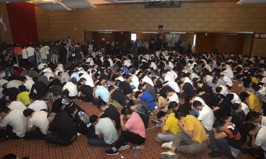 Những người bị bắt ngồi trong tòa nhà ở Putrajaya sau khi chính quyền Malaysia phá vỡ đường dây lừa đảo đầu tư trực tuyến. Ảnh: AP.