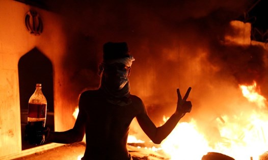 Một người biểu tình Iraq trước lãnh sự quán Iran đang cháy. Ảnh: Reuters