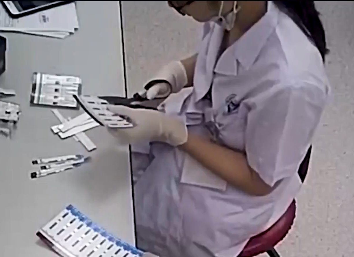 Nhân viên y tế cắt đôi que thử xét nghiệm. Ảnh chụp màn hình từ phóng sự điều tra của VTV24